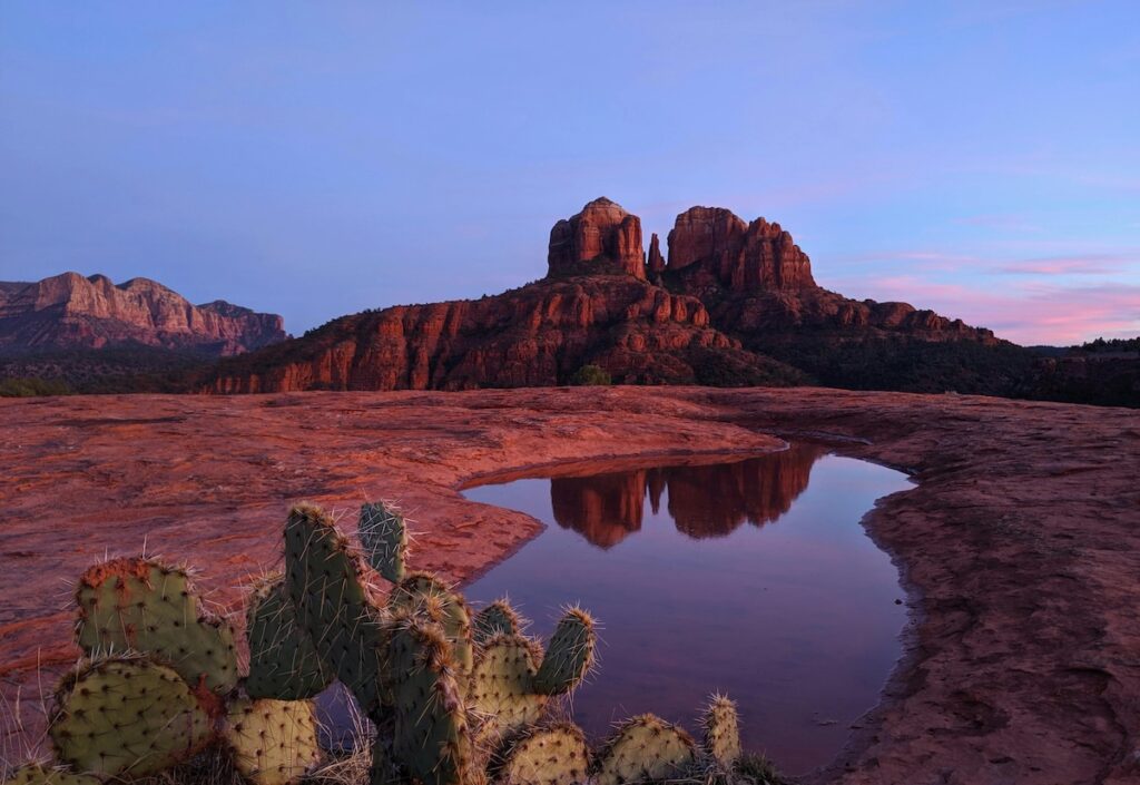 Sedona rock formations at sunset with cactus and water